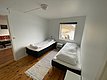 Gemütliches Schlafzimmer in Nord-Norwegen mit zwei Einzelbetten, Holzboden und Fensterblick auf die beeindruckende Küstenlandschaft. Ideal für entspannenden Angelurlaub in skandinavischer Naturkulisse.