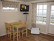 Gemütliches Esszimmer in Nord-Norwegen: Holztisch mit vier Stühlen, TV an der Wand, große Fenster mit Meeresblick. Ideal für Angelurlauber, die Komfort und nordische Umgebung genießen möchten. Entspannung und Abenteuer direkt am Wasser.