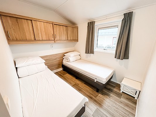 Gemütliches Schlafzimmer in Nordnorwegen mit zwei Einzelbetten, Holzvertäfelung und natürlichem Licht. Ideale Unterkunft für Angelurlaub in skandinavischer Idylle, perfekte Kombination aus Komfort und Abenteuer.