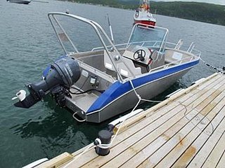 Ein modernes Angelboot ist an einem Holzsteg in Südwest-Norwegen festgemacht, ideal für Meeresangeln. Im Hintergrund ist ein Fjord zu sehen, der Abenteuer und großen Fang verspricht.