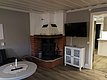 Gemütliches Wohnzimmer mit Kamin, Flachbildfernseher, weißem Beistelltisch und gläsernem Vitrinenschrank für ein modernes Ambiente.