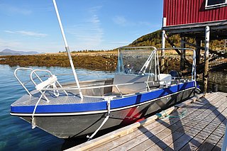 In Südwest-Norwegen liegt ein blaues Angelboot an einem Holzsteg, umgeben von klaren Gewässern und herbstlicher Natur. Ideal für Angelreisen und Meeresangeln.