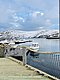 Hafen in Nord-Norwegen mit schneebedeckten Hügeln, ruhigem Wasser und Fischerbooten. Ideal für Angelreisen in faszinierender, nordischer Landschaft. Perfektes Ziel für Abenteurer und Naturfreunde auf der Suche nach Entspannung und großem Fang.
