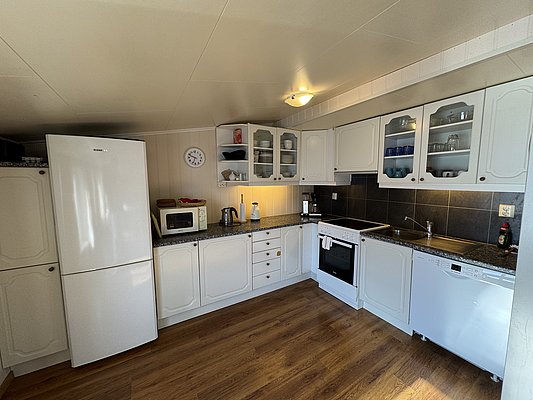 Helle, moderne Küche in Ferienhaus auf Hitra, Norwegen. Ausgestattet mit Kühlschrank, Mikrowelle, Herd und Geschirrspüler. Ideal für Angelurlauber, um frische Fänge zuzubereiten. Angenehme Atmosphäre für erholsame Tage in skandinavischer Natur.