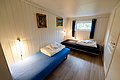 Gemütliches Schlafzimmer in Nordland, Norwegen mit zwei Einzelbetten, hellen Holzwänden, stilvoller Beleuchtung und Naturblick. Ideal für erholsame Nächte während eines Angelurlaubs. Perfekte Kombination aus Komfort und rustikalem Charme.