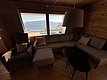 Gemütliches Wohnzimmer in einer norwegischen Hütte auf Hitra, mit großer Fensterfront und Blick aufs Meer. Perfekt für Angelurlaub in Norwegen, Entspannung und Naturgenuss. Ruhige Atmosphäre mit skandinavischem Design.