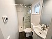 Kompaktes, modernes Badezimmer in Nord-Norwegen mit bodenebener Dusche, weißem Waschbecken und WC. Minimalistisches Design mit Tageslichtfenster. Ideal für komfortable Angelreisen.