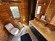 Modernes Badezimmer in einer Holzhütte auf Hitra, Norwegen. Helle Holzwände, Doppelwaschbecken, zwei Fenster, Toilette. Ideal für Anglerurlaub, kombiniert Komfort mit Naturerlebnis in skandinavischem Design. Entdecke Angelreisen in wunderschöner Umgebung.