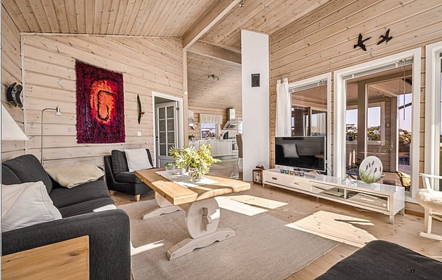 Gemütliches skandinavisches Wohnzimmer in Südwest-Norwegen mit Holzwänden, großer Fensterfront und moderner Einrichtung. Helle, einladende Atmosphäre – idealer Rückzugsort nach einem erfolgreichen Angelabenteuer. Perfekt für Erholung und Entspannung.