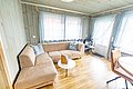 Gemütlicher Wohnbereich in Nord-Norwegen mit beiger Eckcouch, kleinem Tisch, Holzfußboden und großen Fenstern. Ideal für entspannte Angelreisen. Helles, einladendes Ambiente mit skandinavischem Flair. Perfekter Rückzugsort nach einem gelungenen Angeltag.