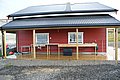 Rotes Holzhaus mit überdachter Terrasse und Fischvorbereitungsstation in Nord-Norwegen. Perfekt für Angelurlaube, bietet es praktischen Komfort und eine ideale Basis für Meeresangeln-Abenteuer.