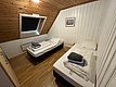 Gemütliches Doppelzimmer in einer Holzhütte, Hitra, Norwegen. Helle Holzverkleidung, Dachschräge, Tageslichtfenster, zwei Einzelbetten, vorbereitet mit Handtüchern. Ideal für erholsamen Angelurlaub. Perfekt für Natur- und Meeresangeln-Fans.