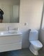 Ein modernes Badezimmer mit weißen Fliesen, einem Waschbecken, einem Spiegel und einer Toilette. Ein modernes Badezimmer mit weißen Fliesen, einem Waschbecken, einem Spiegel und einer Toilette.
