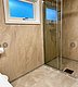 Modernes Badezimmer in Hitra, Norwegen, mit begehbarer Dusche, eleganten beigen Fliesen und Fenster für Tageslicht. Komfortable Unterkunft für Angelreisende. Perfekte Kombination aus Funktionalität und Stil für einen erholsamen Urlaub.
