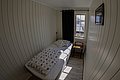 Kleines, gemütliches Einzelzimmer in Nord-Norwegen, mit holzverkleideten Wänden und einem Fenster, das Tageslicht hineinlässt. Ideal für einen erholsamen Angelurlaub.