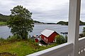 Ein traditionelles rotes Fischerhaus liegt idyllisch am Ufer der Küste von Hitra, Norwegen, umgeben von lebendigem Grün und ruhigem Wasser – ideal für einen entspannenden Angelurlaub in der Natur.