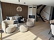 Ein modernes skandinavisches Wohnzimmer in Südwest-Norwegen mit eleganter Holzvertäfelung, bequemen Möbeln, rundem Couchtisch, Kamin und stilvoller Treppe. Perfekt für Erholung nach einem abenteuerlichen Angelurlaub in Norwegen.