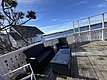 Holzterrasse mit gemütlichen Rattanmöbeln, umgeben von malerischer Küstenlandschaft bei Hitra, Norwegen. Perfekt für Angelurlaub, mit Blick auf blaues Meer und entfernte Inseln. Entspanne und genieße die Naturidylle am Wasser.