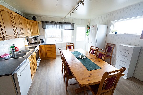 Helle, einladende Küche in Nordland, Norwegen, mit Holzmöbeln, großem Esstisch, moderner Ausstattung und natürlichem Licht – ideal für Angelreisende.