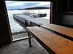 Angelsteg mit Bootsanleger vor malerischer Küste in Nord-Norwegen. Blick aus einer Hütte auf Fjord, Berge und ruhig daliegendes Wasser. Ideale Kulisse für Angelreisen und Meeresabenteuer.