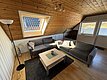 Gemütlicher Wohnraum in Hitra, Norwegen, mit Dachschräge, grauen Sofas und Blick aufs Wasser. Perfekt für Angelurlauber, die Komfort und Naturerlebnis kombinieren möchten. Ideal für entspannte Abende nach erfolgreichen Angelausflügen.