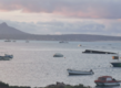 Küstenpanorama bei Sonnenuntergang in São Vicente, Kapverden: Mehrere Boote auf ruhigem Meer, dahinter eine felsige Insel. Wolken und sanftes Abendlicht schaffen eine friedliche Atmosphäre. Ideal für einen erholsamen Angelurlaub.