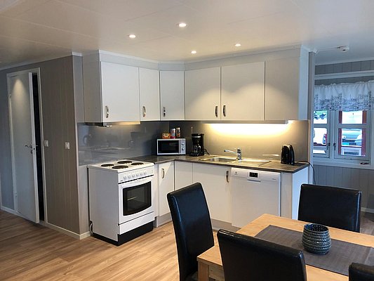 Helle, moderne Küche in Nord-Norwegen mit Kochherd, Mikrowelle und Geschirrspüler. Ideal für Angelreisende, die Komfort und Praktikabilität schätzen. Perfekt für entspannte Abende nach erfolgreichen Angelausflügen.
