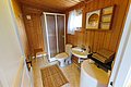 Ein gemütliches, holzvertäfeltes Badezimmer auf Hitra, Norwegen. Enthält moderne Dusche, Waschbecken, Toilette und Handtücher. Ideal für einen erholsamen Angelurlaub mit Komfort und Naturverbundenheit.