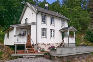Charmantes weißes Holzhaus in Hitra, Norwegen, umgeben von üppiger Natur. Ideal für erholsame Angelreisen, bietet es gemütliche Unterkünfte und eine perfekte Ausgangslage für Angelabenteuer. Entspannung pur in skandinavischer Idylle.