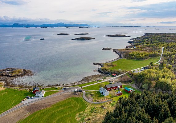 Luftaufnahme von Hitra, Norwegen: Malerische Küste mit verstreuten Inseln, grünen Wiesen und roten Häusern. Idealer Ort für Angelreisen und Naturerlebnisse. Klarer Himmel, ruhiges Meer, perfekt für Meeresangeln und Erholung.