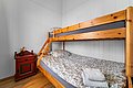 Kompaktes Schlafzimmer mit Etagenbett aus Holz und gemütlicher Bettwäsche in Nord-Norwegen. Rote Kommode mit Vase und Blumen verleiht rustikalen Charme. Perfekt für erholsame Nächte während Angelreisen.