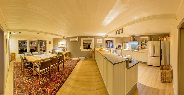 Gemütliches Ferienhaus in Nordland, Norwegen: Helles Wohnzimmer mit Esstisch, moderner Küche, edlem Holzboden und stilvollem Teppich. Perfekt für Angelurlaube, umgeben von atemberaubender Natur und reicher Meeresfauna.