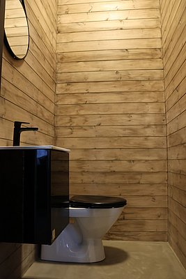 Modernes Badezimmer in Nordland, Norwegen: Holzverkleidete Wände, Waschbecken mit Spiegel, Toilette. Skandinavisches Design vereint natürliche Materialien und schlichtes Ambiente. Ideal für erholsame Momente nach einem aufregenden Angelausflug.