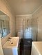 Modernes Badezimmer in Nord-Norwegen mit ebenerdiger Dusche, weißem Waschbecken und Toilette. Helle Fliesenwände und dunkle Bodenfliesen bieten einen stilvollen, sauberen Look. Ideal für Komfort nach einem angelreichen Tag.