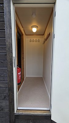 Kleiner, gut beleuchteter Raum in Nordland, Norwegen, mit Holzelementen und Feuerlöscher. Perfekt als sicherer Stauraum oder Angelausrüstungslagerung für einen Angelurlaub in der malerischen Region.
