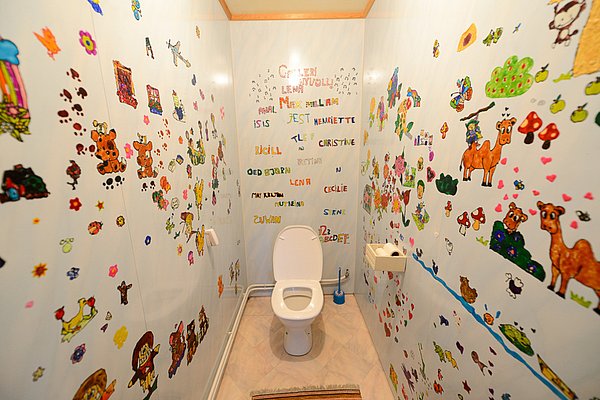 Bunt bemaltes Badezimmer in Nord-Norwegen mit kindlichen Zeichnungen an den Wänden. Lebhafte Motive wie Tiere und Blumen schaffen eine fröhliche Atmosphäre. Barrierefrei und kreativ gestaltet für Besucher jeden Alters.