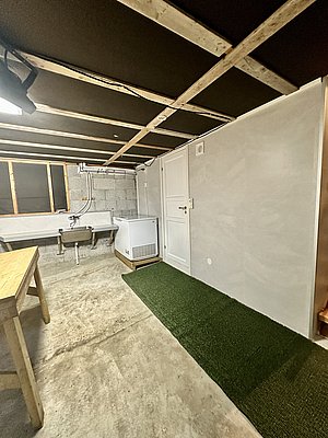Kellerraum in Nord-Norwegen, ideal für Outdoor-Aktivitäten-Vorbereitung, mit Tisch, Waschbecken und Gefriertruhe. Perfekt für Angler zur Fischverarbeitung und Ausrüstungslagerung in rustikaler Umgebung.