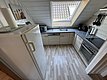 Kompakte, moderne Küche in einer Ferienunterkunft in Hitra, Norwegen. Ausgestattet mit Kühlschrank, Herd, Mikrowelle und Dachfenster. Ideal für Angelurlauber, die nach einem langen Tag am Meer bequem kochen möchten. Optimale Selbstversorger-Möglichkeiten.