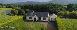 Einsam gelegenes Cottage in Bundoran, Irland, umgeben von grünen Wiesen und einem Fluss. Ideal für Naturliebhaber und Angler. Atemberaubende Bergkulisse im Hintergrund, perfekte Kulisse für Erholung und Angelabenteuer.