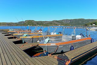 Boote liegen ruhig am Steg in der malerischen Küstenlandschaft Südwest-Norwegens. Perfekter Ausgangspunkt für Angelreisen, Meeresangeln und Abenteuer inmitten unberührter Natur und klarer Gewässer.