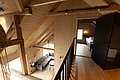 Gemütliches nordisches Holzinterieur in Nordland, Norwegen. Offener Wohnbereich mit Sitzgruppe und modernem Schlafzimmer auf einer Empore. Ideal für erholsame Angelurlaube und Naturerlebnisse.