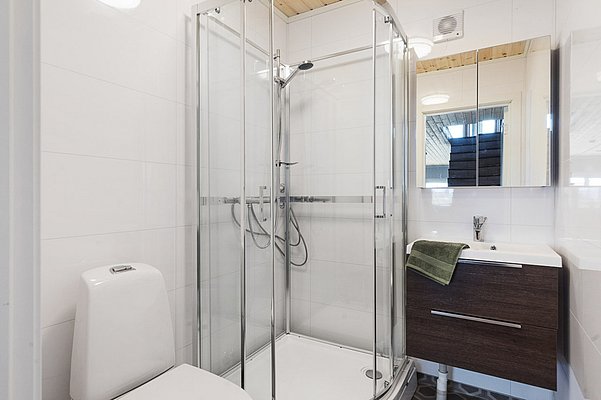 Modernes Badezimmer in Nordland, Norwegen, mit Glasduschkabine, Holzdecke, weiß gefliesten Wänden und dunklem Waschtischunterschrank. Ideal für einen komfortablen Angelurlaub in einer stilvollen Unterkunft.