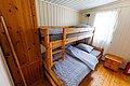 Gemütliches Schlafzimmer in Hitra, Norwegen, mit Etagenbett aus Holz, Schrank und Nachttisch. Ideal für Angelreisen, bietet komfortable Unterkunft in rustikalem Ambiente. Perfekt zum Entspannen nach einem erfolgreichen Tag am Meer.