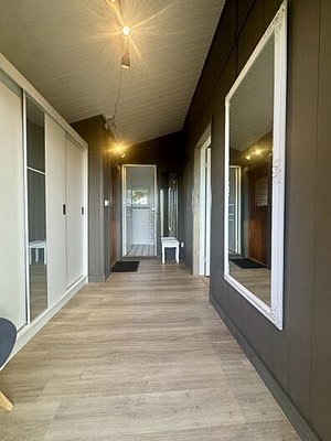 Moderner Eingangsbereich in Nordland, Norwegen: Helle Holzfußböden, großer Spiegel, stilvolle Beleuchtung und weiße Einbauschränke schaffen ein einladendes Ambiente. Perfekt für Angelreisende, die Komfort und skandinavisches Design schätzen.
