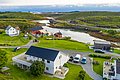 Norwegische Küstenidylle in Nordland: Malerische Holzhäuser am Wasser, umgeben von üppig grüner Landschaft und sanften Hügeln. Ein perfektes Ziel für einen unvergesslichen Angelurlaub im hohen Norden, ideal zum Entspannen und Entdecken.