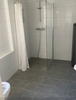 Ein modernes Badezimmer mit bodengleicher Dusche, Duschvorhang und grauen Fliesen. Ein modernes Badezimmer mit bodengleicher Dusche, Duschvorhang und grauen Fliesen.