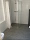 Ein modernes Badezimmer mit bodengleicher Dusche, Duschvorhang und grauen Fliesen. Ein modernes Badezimmer mit bodengleicher Dusche, Duschvorhang und grauen Fliesen.