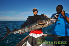 Zwei Angler auf den Malediven präsentieren stolz ihren beeindruckenden Fang: einen großen Speerfisch. Blaues Meer und klarer Himmel im Hintergrund. Ideal für Angelenthusiasten, die Meeresangeln und Abenteuer suchen.