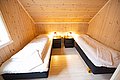 Gemütliches Schlafzimmer in Nordland, Norwegen mit zwei Einzelbetten aus Holz, warm beleuchtet. Ideal für Angelurlauber, die Entspannung nach einem erfolgreichen Angeltag suchen. Perfekte Mischung aus Komfort und nordischer Gemütlichkeit.