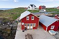 Rote Holzhäuser direkt am Meer in Nordland, Norwegen. Malerische Landschaft mit grünen Hügeln und felsigen Küsten. Ideal für einen erholsamen Angelurlaub und unvergessliche Outdoor-Abenteuer. Perfekt für Natur- und Meeresliebhaber.
